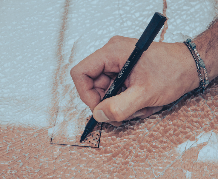Prova di rottura del vetro mano con pennarello e disegno su vetri rotti