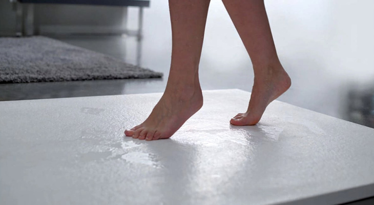 White colored wet shower tray with person walking on top